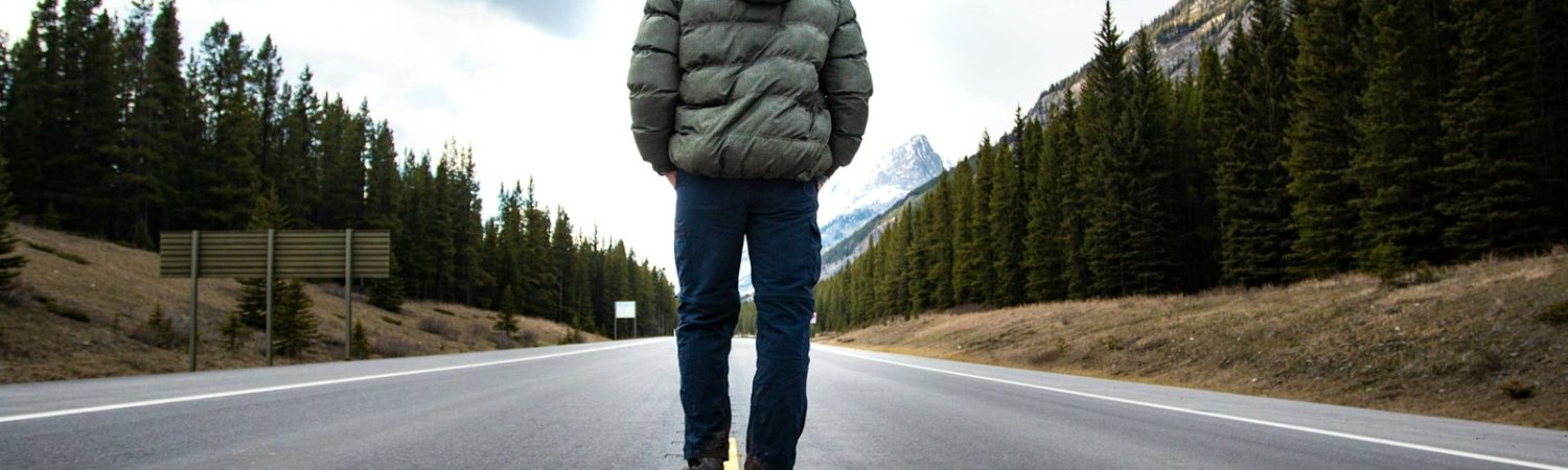 A person standing on an open mountain road