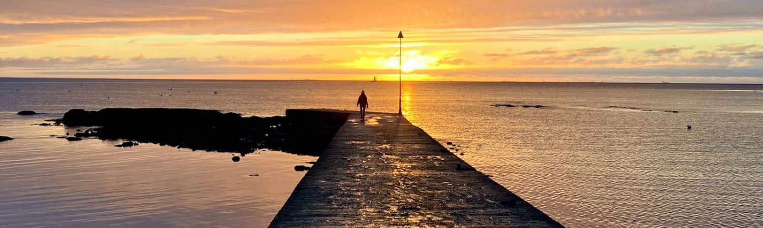 A person walking on a pier at sunset