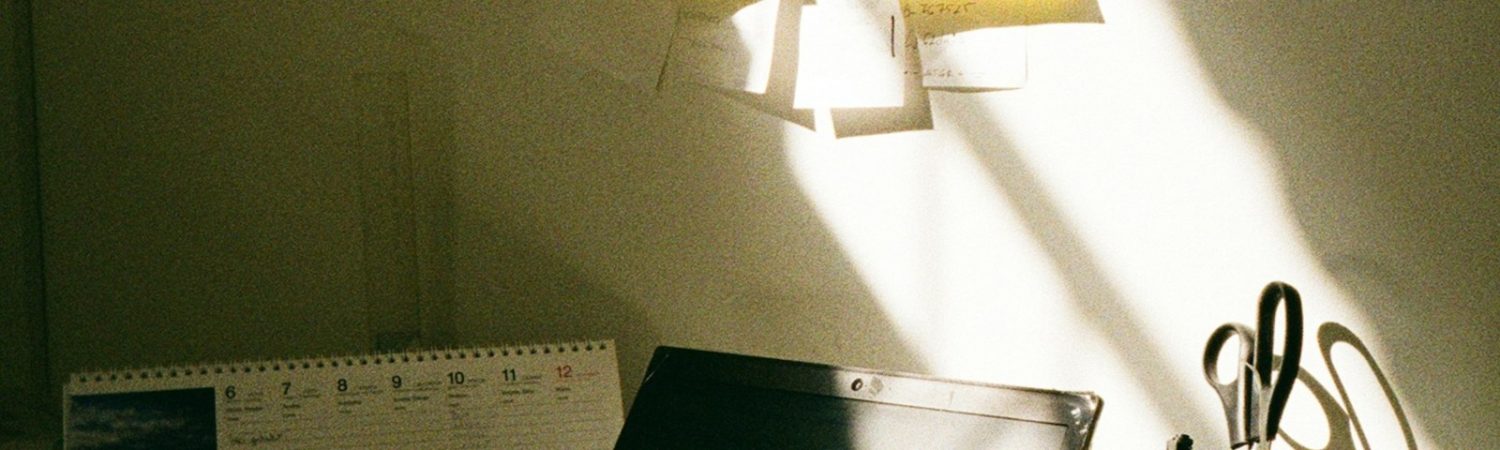 A planning desk with calendar, sticky notes, and scissors in sunlight