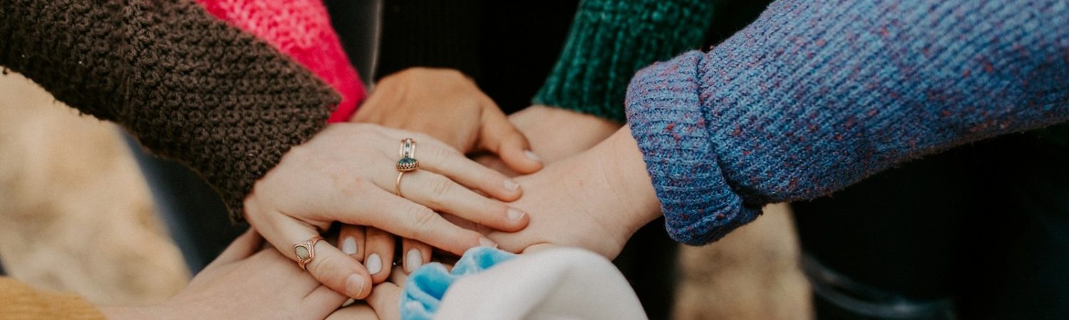 Several people stacking their hands together