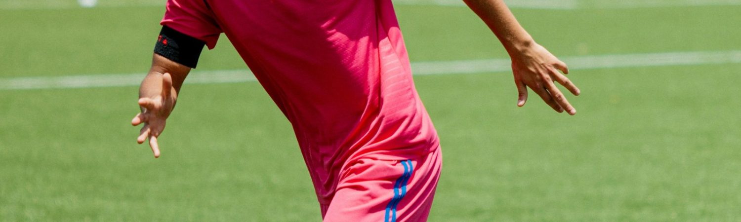 A soccer player running across a green field