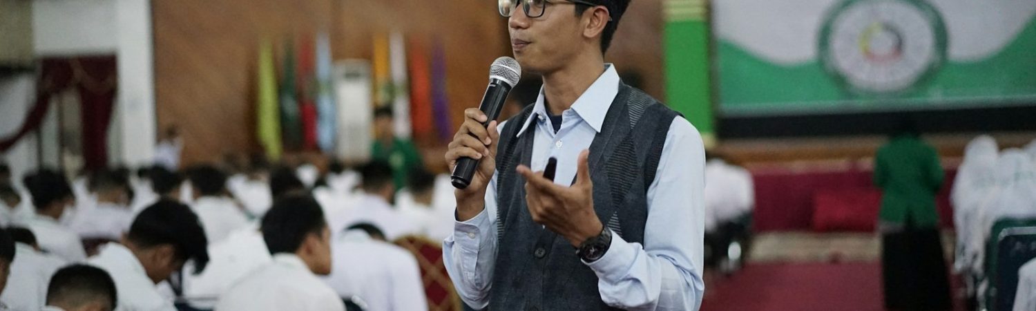 A person speaking into a microphone before an audience
