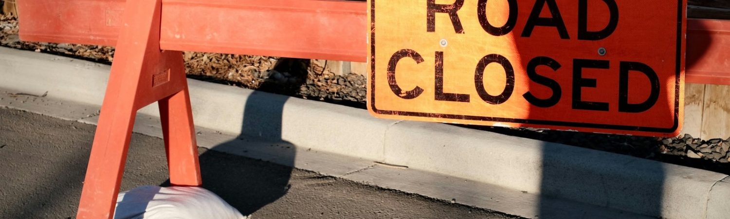 A road closed construction barrier on asphalt