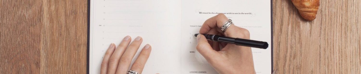 A hand writing notes at a desk